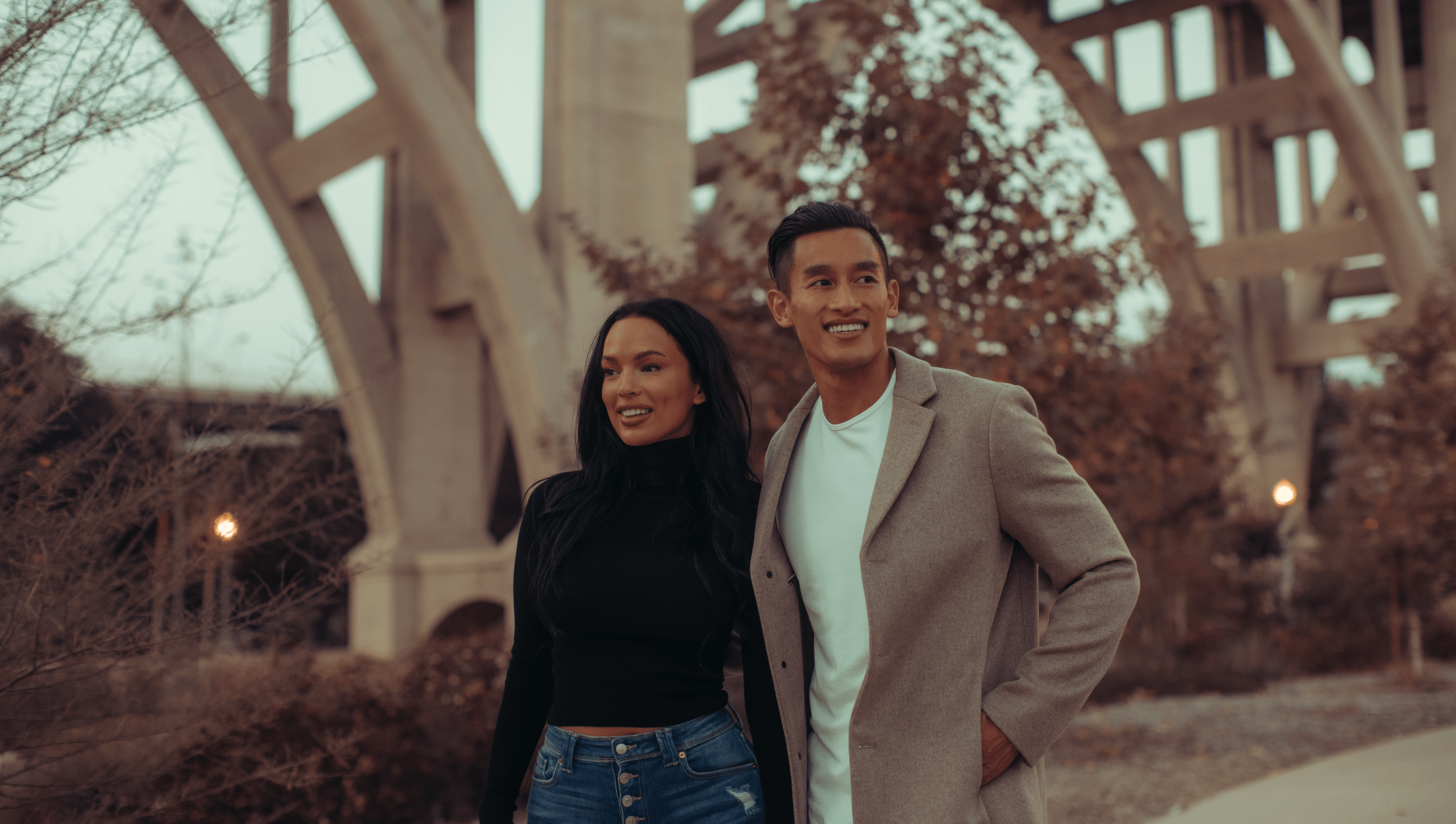 Fashionable couple standing outside by a bridge